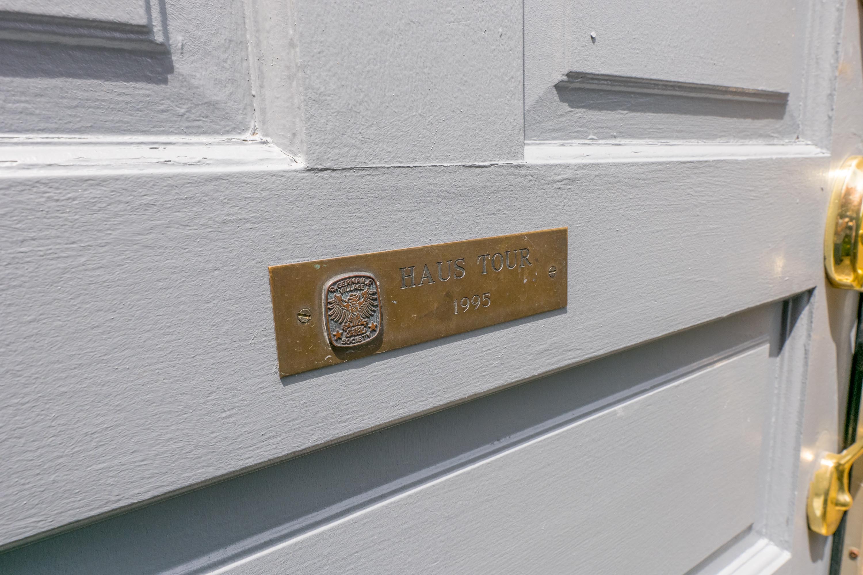 A brass &ldquo;Haus Tour 1995&rdquo; plaque on the front door.